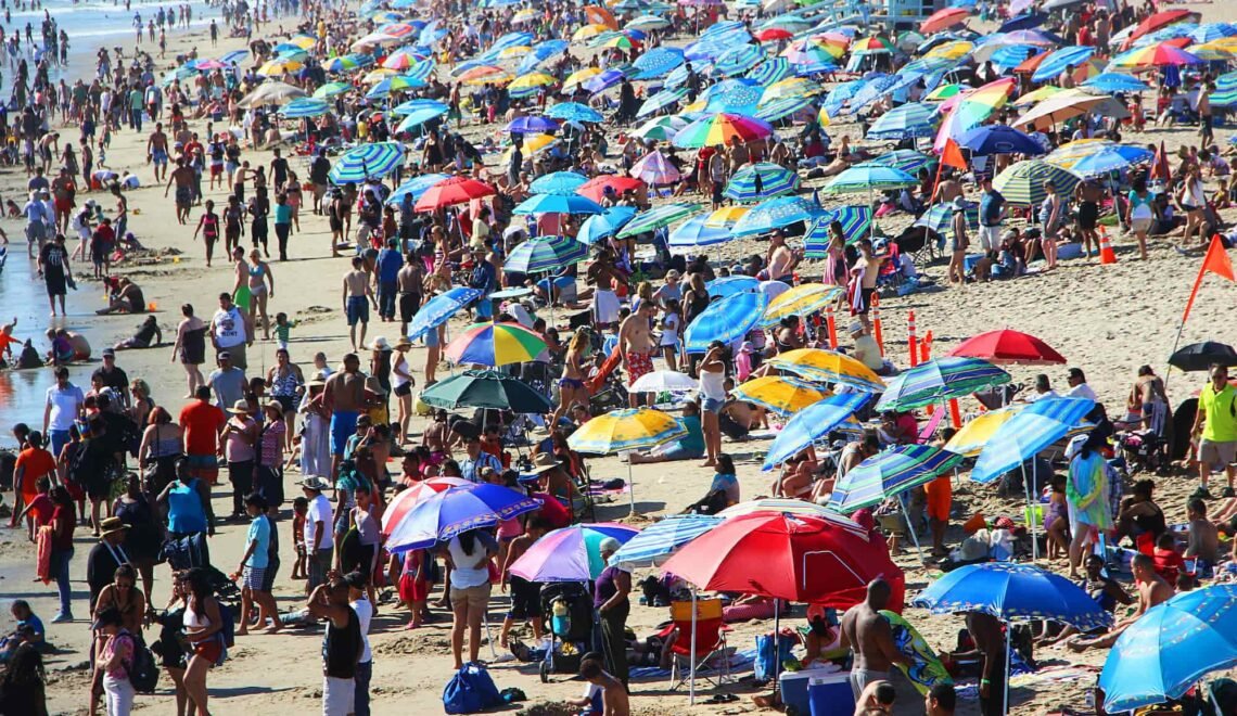 Playa con muchas personas en un día soleado y de vacaciones.